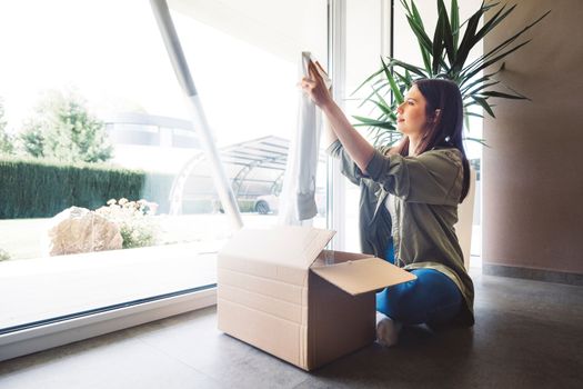 Young caucasian woman receiving a big box of her online orders. Woman opening the package, getting excited to see the stuff she bought. High quality photo