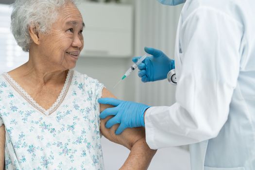 Elderly Asian senior woman wearing face mask getting covid-19 or coronavirus vaccine by doctor make injection.