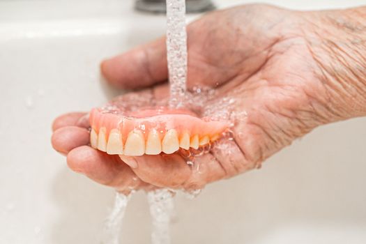 Asian elderly woman patient holding to use denture, healthy strong medical concept.