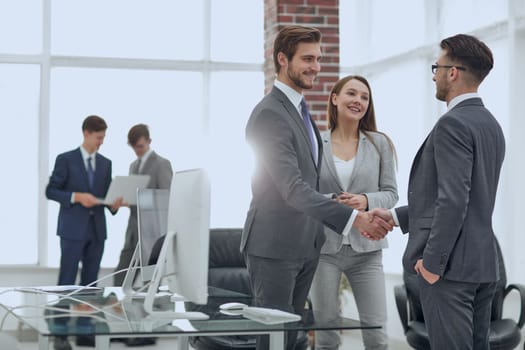 Partners concluding deal and shaking hands in the presence of team members