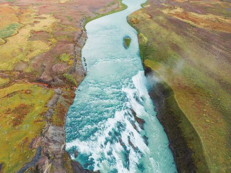 Huge beautiful waterfall Gullfoss, famous landmark in Iceland. River foaming whilst falling down the waterfall, tourist waling by, looking at the waterfall from a view point. High quality photo