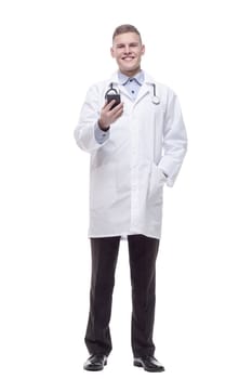 in full growth. young doctor with a smartphone. isolated on a white background.