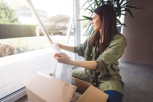 Young caucasian woman receiving a big box of her online orders. Woman opening the package, getting excited to see the stuff she bought. High quality photo