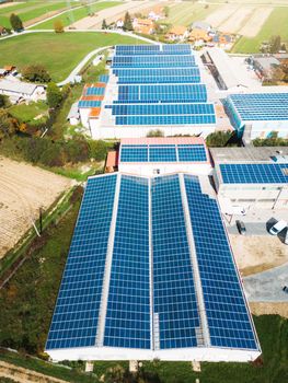 Solar panels installed on a roof of a large industrial building or a warehouse. Industrial building in the country side of Slovenia with residential houses in the background. High quality photo