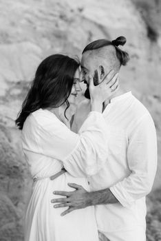 a guy with a girl in white clothes on the seashore next to clay cliffs