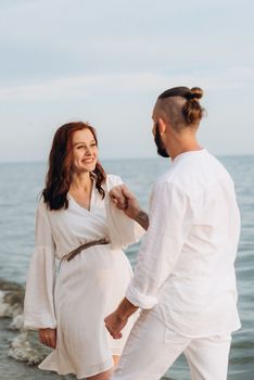 a guy with a girl in white clothes on the seashore next to clay cliffs