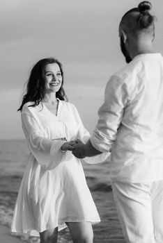 a guy with a girl in white clothes on the seashore next to clay cliffs