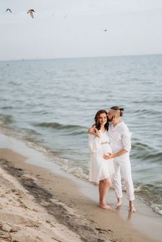 a guy with a girl in white clothes on the seashore next to clay cliffs