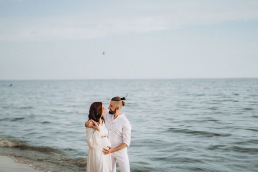 a guy with a girl in white clothes on the seashore next to clay cliffs