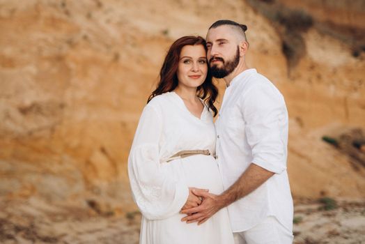 a guy with a girl in white clothes on the seashore next to clay cliffs