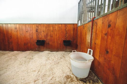 Empty stable, no horses inside the stables. Clean and empty horse boxes with fresh hay at the ranch. 