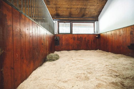 Empty stable, no horses inside the stables. Clean and empty horse boxes with fresh hay at the ranch. 