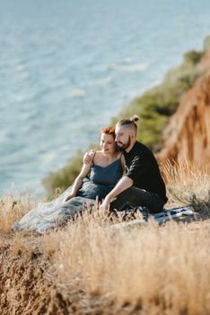 pregnant girl and boyfriend on high hills near the sea