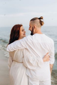 a guy with a girl in white clothes on the seashore next to clay cliffs