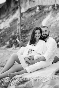 pregnant girl and boyfriend on a picnic by the sea in white clothes