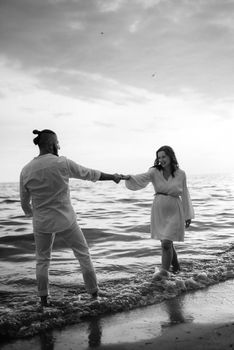 a guy with a girl in white clothes on the seashore next to clay cliffs