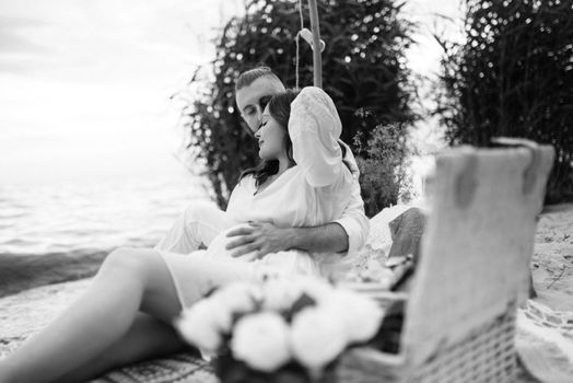 pregnant girl and boyfriend on a picnic by the sea in white clothes