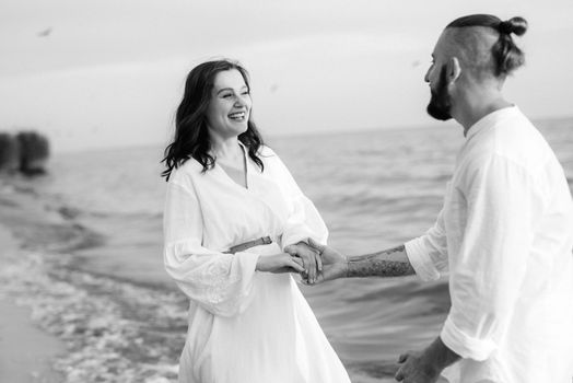 a guy with a girl in white clothes on the seashore next to clay cliffs