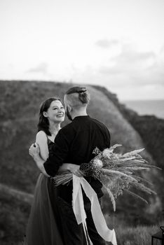 wedding ceremony of a girl and a guy on high hills near the sea