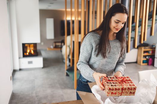 Cheerful young woman excited over a package she just received. Woman getting her christmas gift in the mail. Opening the Christmas present at home.