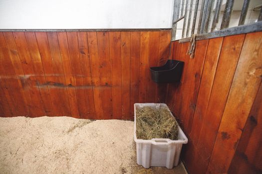 Empty stable, no horses inside the stables. Clean and empty horse boxes with fresh hay at the ranch. 