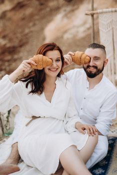 pregnant girl and boyfriend on a picnic by the sea in white clothes