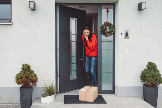 Cheerful young woman excited over a package she just received. Woman getting her christmas gift in the mail. Opening the Christmas present at home.