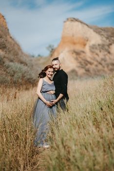 pregnant girl and boyfriend on high hills near the sea