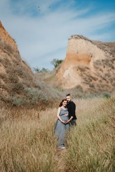 pregnant girl and boyfriend on high hills near the sea