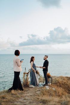 wedding ceremony of a girl and a guy on high hills near the sea