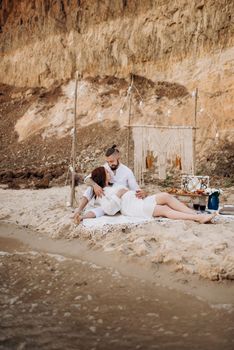 pregnant girl and boyfriend on a picnic by the sea in white clothes