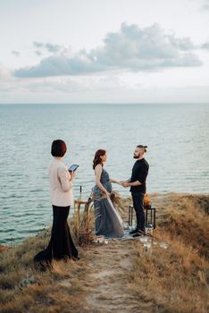 wedding ceremony of a girl and a guy on high hills near the sea