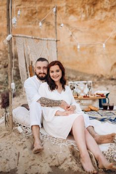 pregnant girl and boyfriend on a picnic by the sea in white clothes