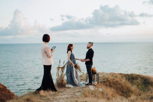 wedding ceremony of a girl and a guy on high hills near the sea