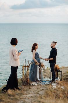 wedding ceremony of a girl and a guy on high hills near the sea