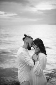 a guy with a girl in white clothes on the seashore next to clay cliffs