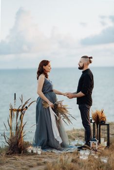 wedding ceremony of a girl and a guy on high hills near the sea