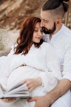 pregnant girl and boyfriend on a picnic by the sea in white clothes