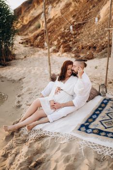 pregnant girl and boyfriend on a picnic by the sea in white clothes