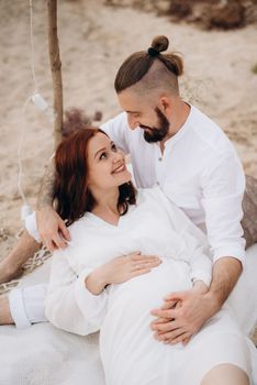 pregnant girl and boyfriend on a picnic by the sea in white clothes