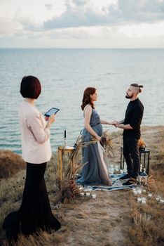 wedding ceremony of a girl and a guy on high hills near the sea