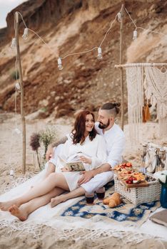 pregnant girl and boyfriend on a picnic by the sea in white clothes