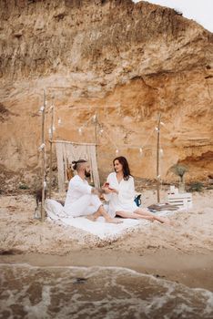 pregnant girl and boyfriend on a picnic by the sea in white clothes