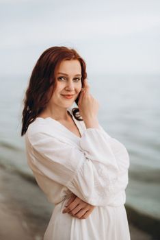 pregnant girl with brown hair on the seashore in white clothes