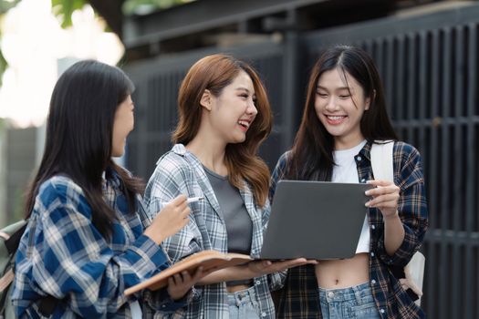 Beautiful young Asian woman college student with friends at outdoors. College student working on the college campus.