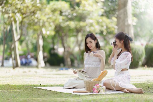 Beautiful woman and friend having picnic on sunny spring day in outdoor park. Valentine and LGBT concept.