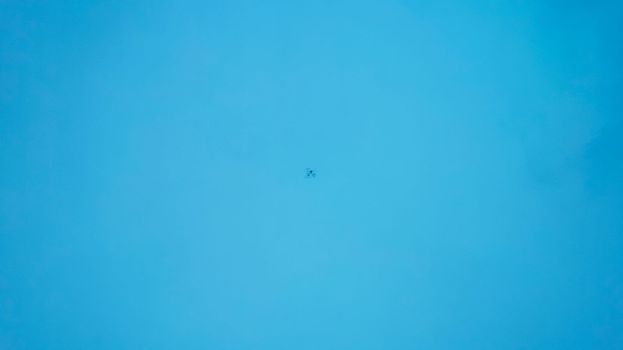 Top view of the turquoise surface of the lake water. A small ripple from the waves and a slight gradient from light blue to dark blue. Photo as a background. The drone is reflected in the water