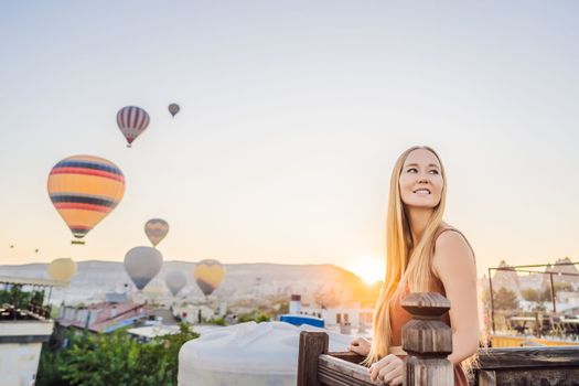 Tourist woman looking at hot air balloons in Cappadocia, Turkey. Happy Travel in Turkey concept. Woman on a mountain top enjoying wonderful view.