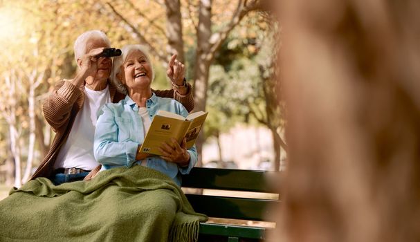 Bird watching, book and senior couple in a park, retirement hobby and holiday adventure in Sweden. Bird search, elderly smile and man and woman with knowledge of animals and binoculars in nature.