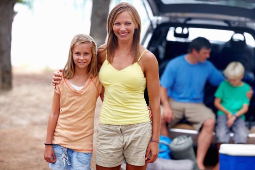 Mother and daughter smiling. Portrait of mother and daughter smiling with family in background